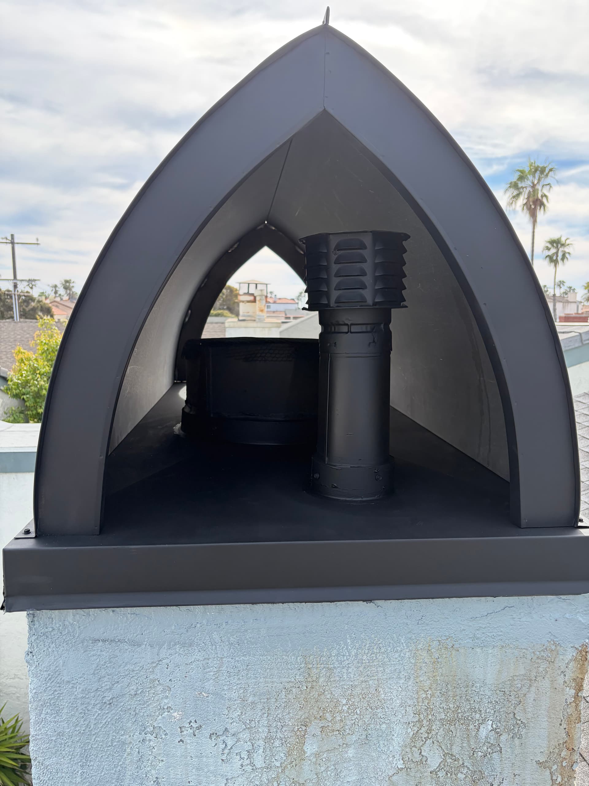 Close-up detail of black chimney shroud with flue pipe and spark arrestor
