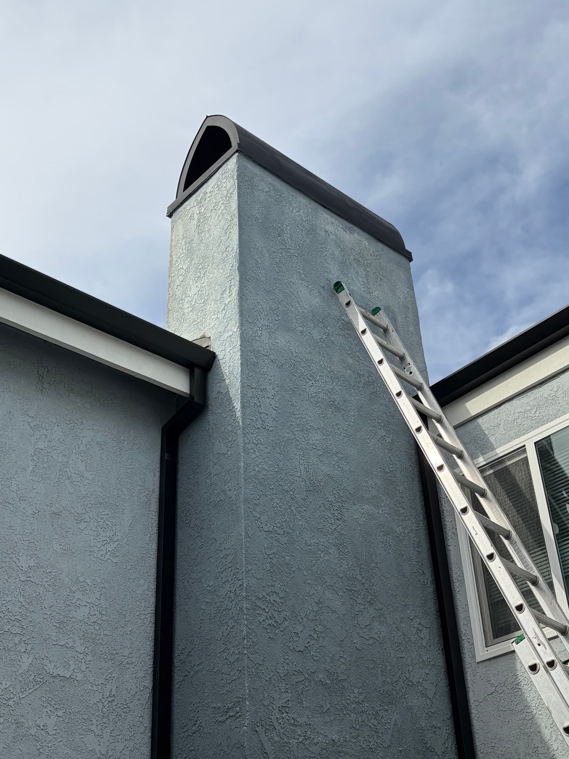 Black chimney shroud corner angle showing clean edge detail on stucco chimney