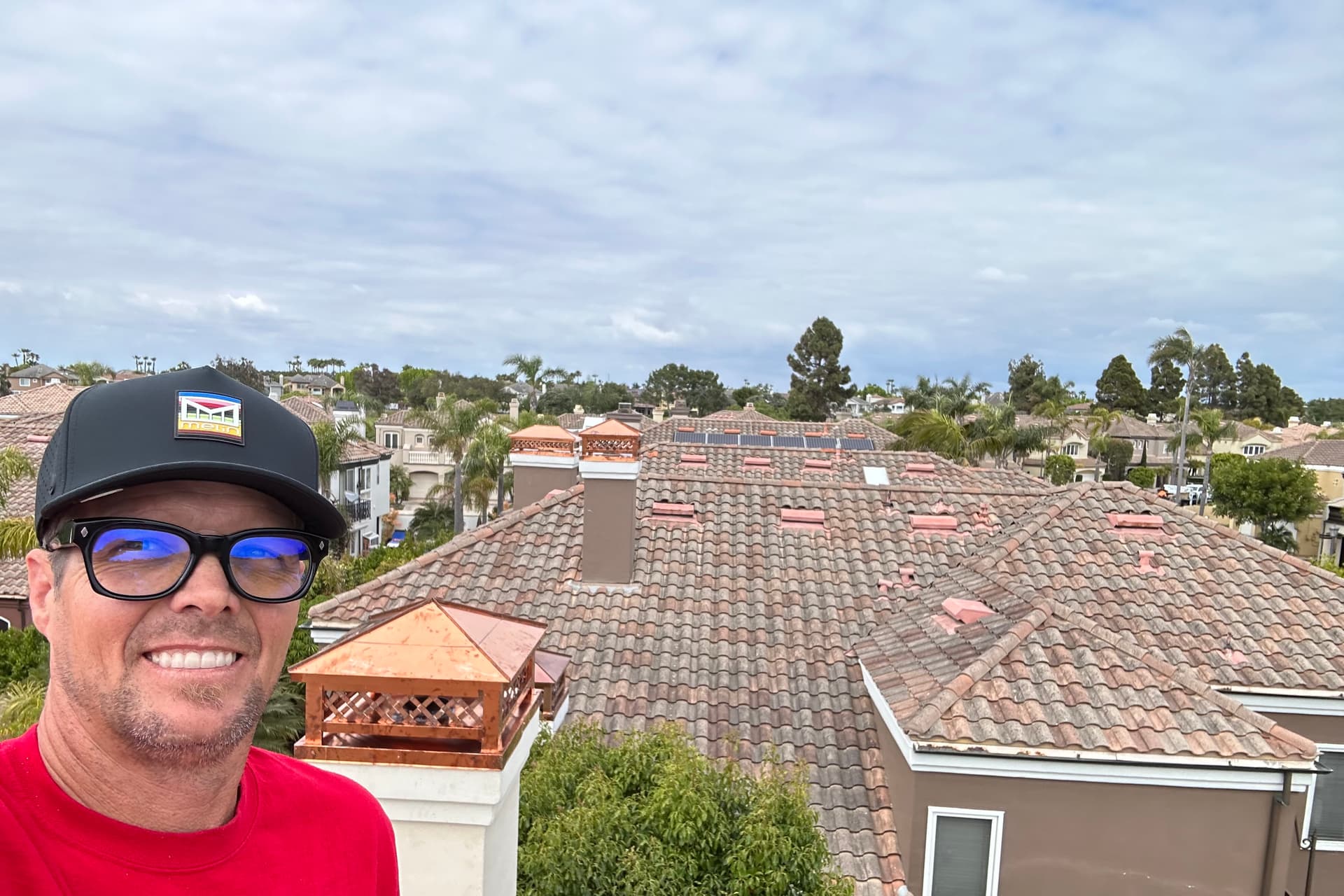 Rain Gutter Guys installer on rooftop with completed copper chimney cap