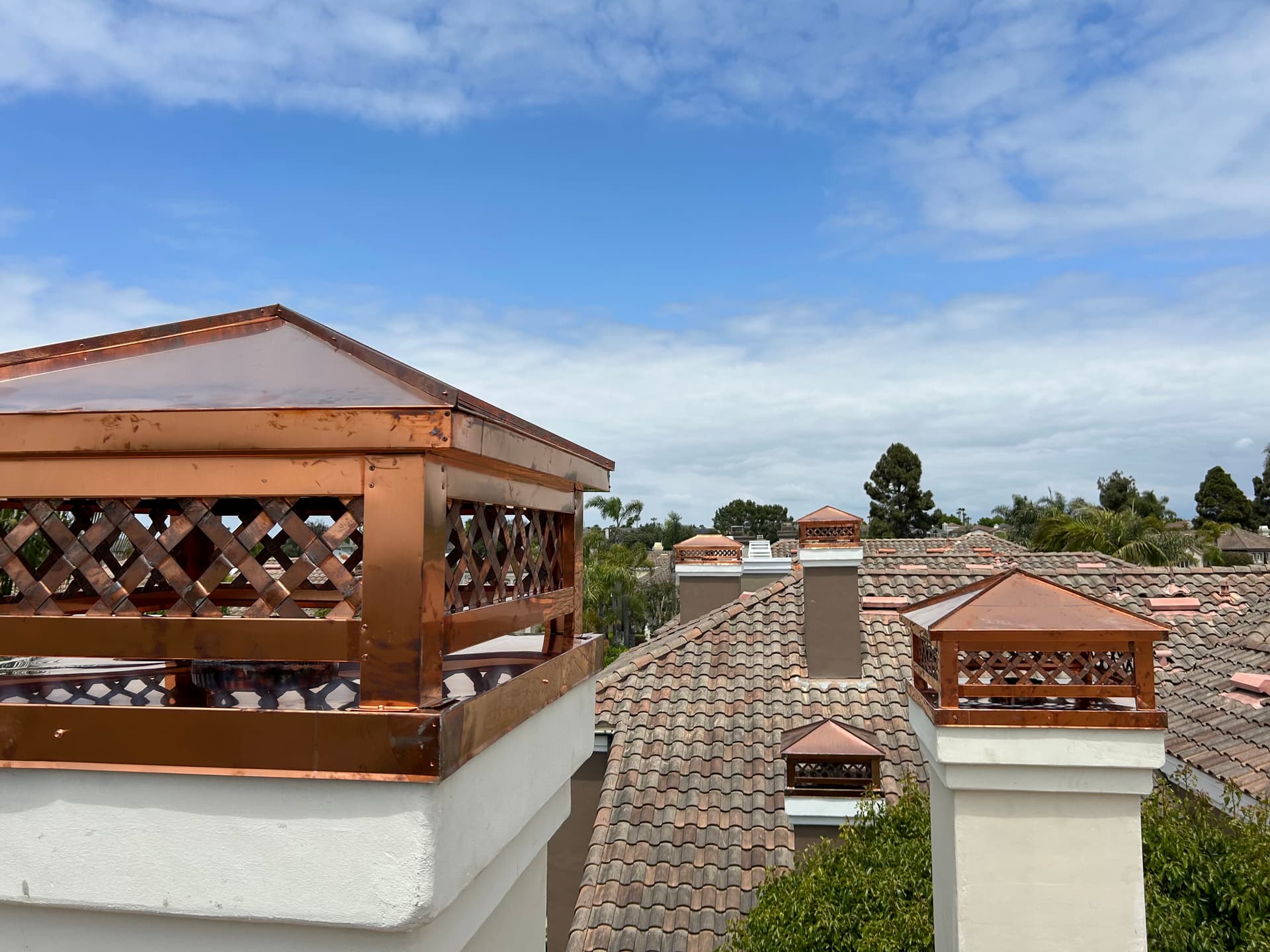 Copper chimney caps and shrouds installed on a tile roof in Southern California
