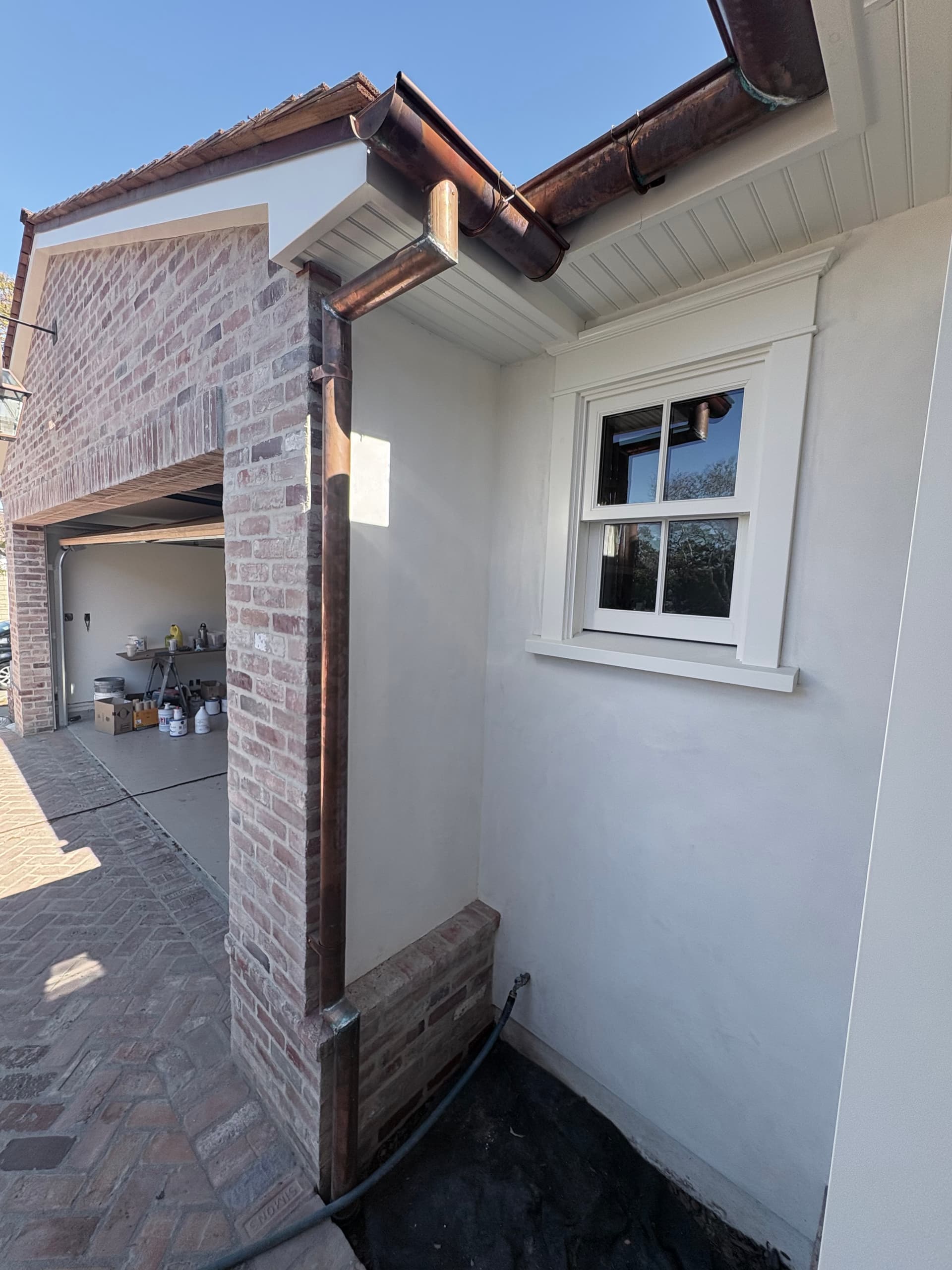 Copper downspout and gutter at brick corner with window detail