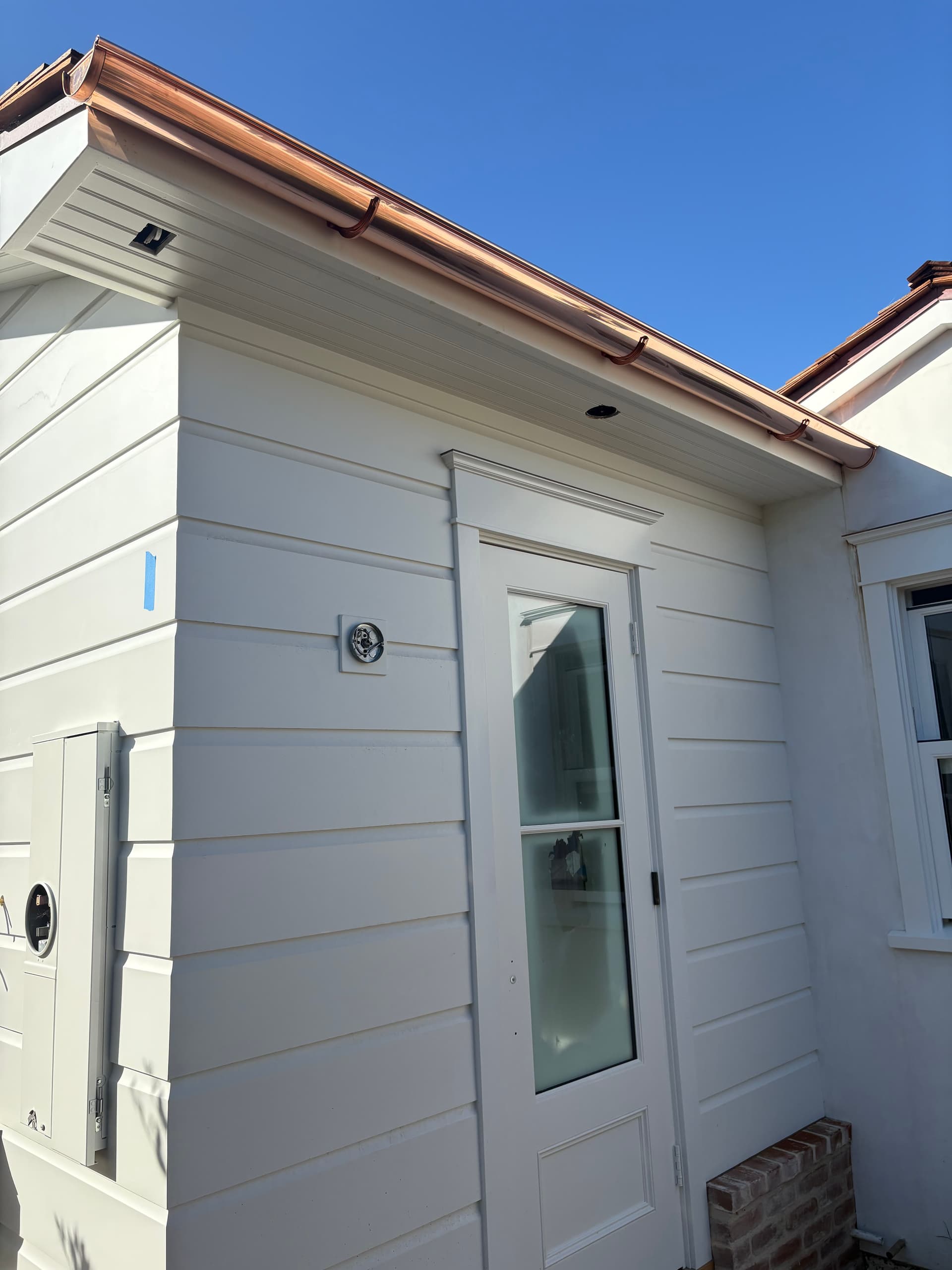 Copper gutter running along a modern board-and-batten home exterior