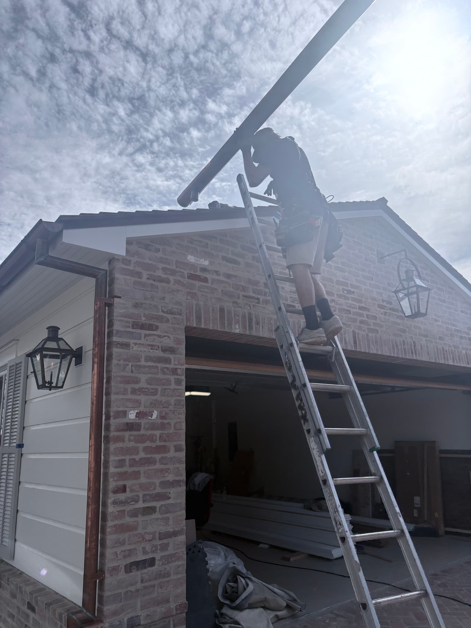 Rain Gutter Guys installer on ladder installing copper half-round gutter
