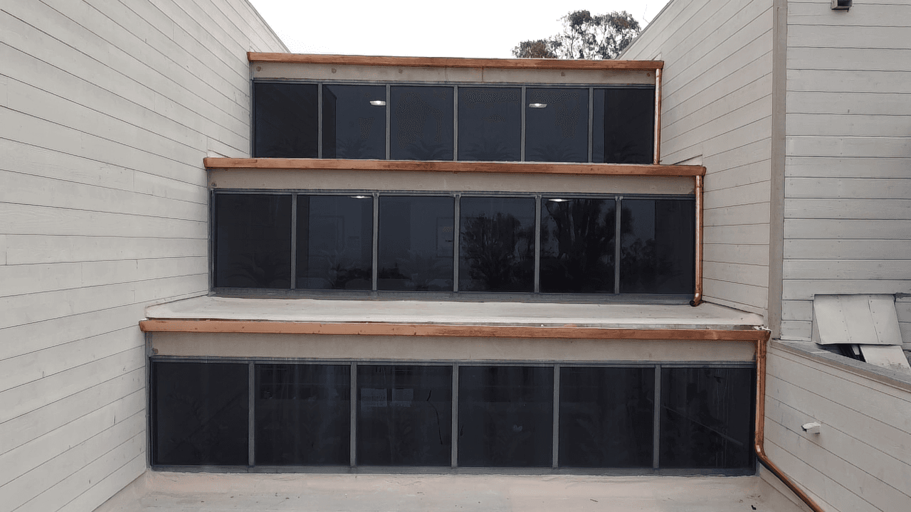 Copper gutter installation on tiered window facade with three levels