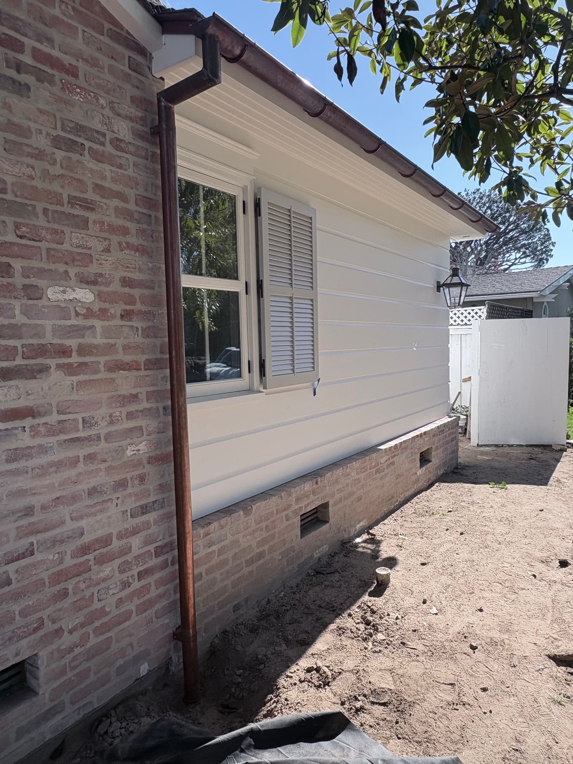 Copper half-round gutter along brick siding with board-and-batten