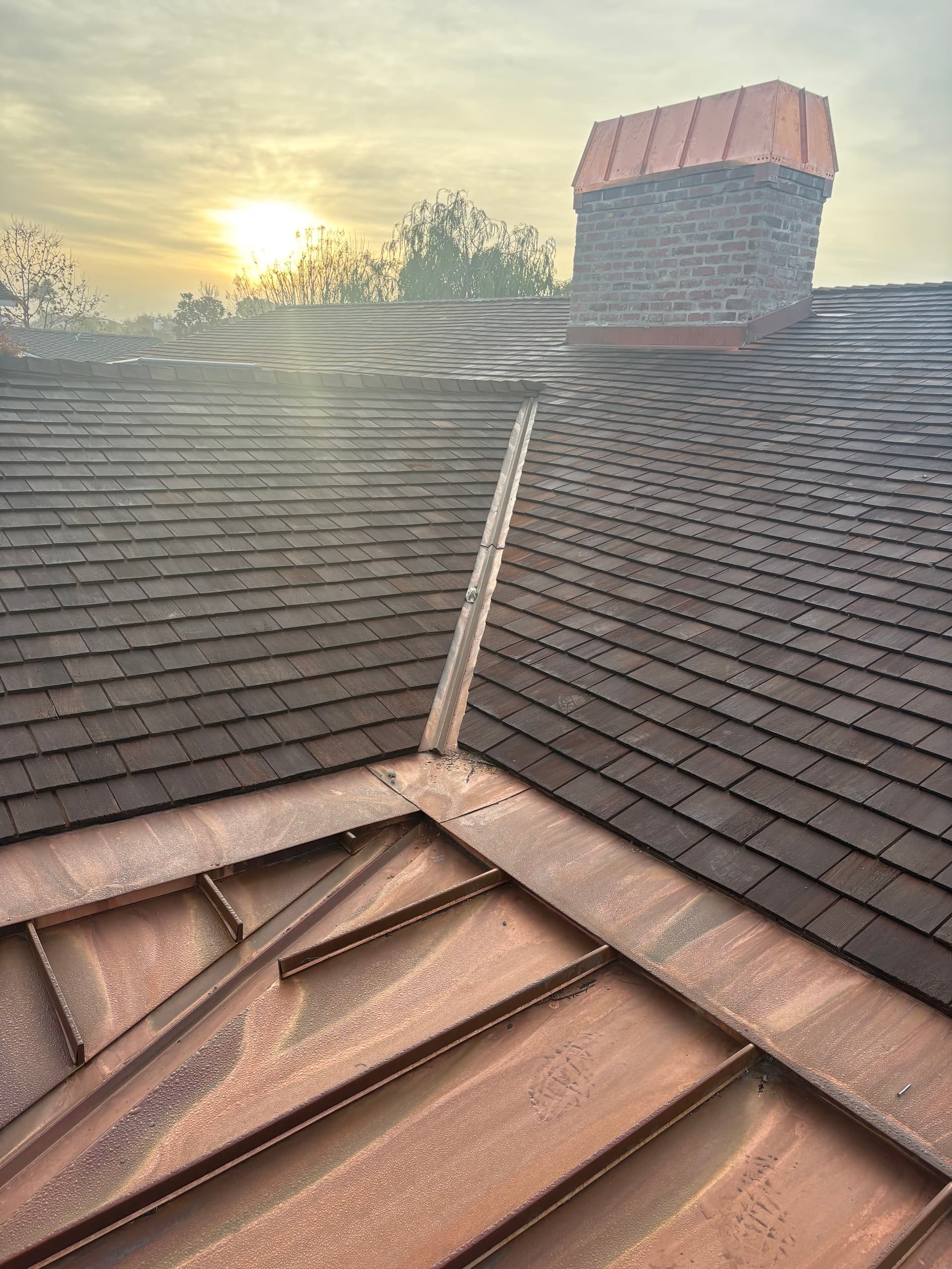 Copper roof flashing and chimney cap at sunset