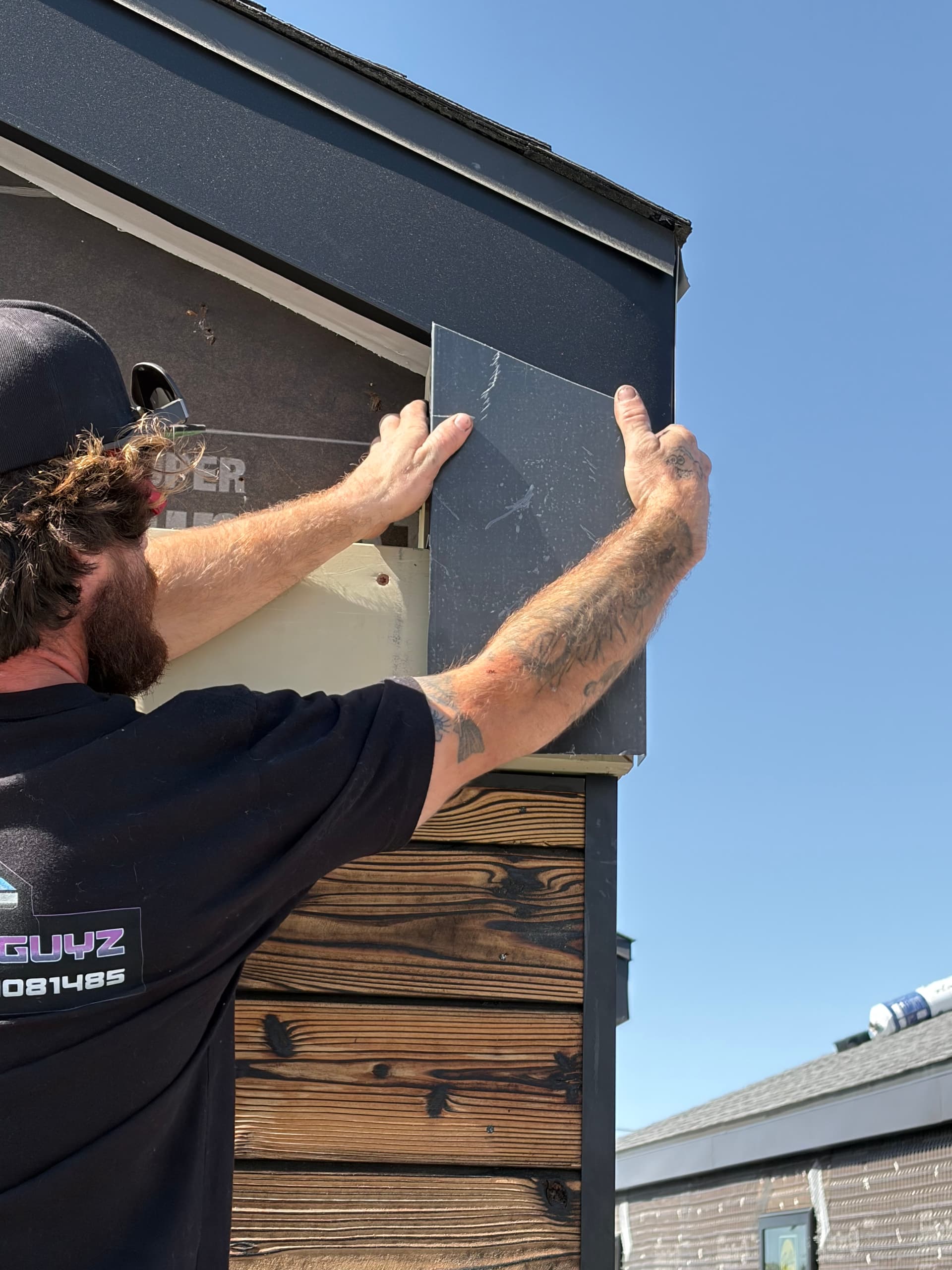 Installer positioning aluminum fascia wrap panel on eave underside