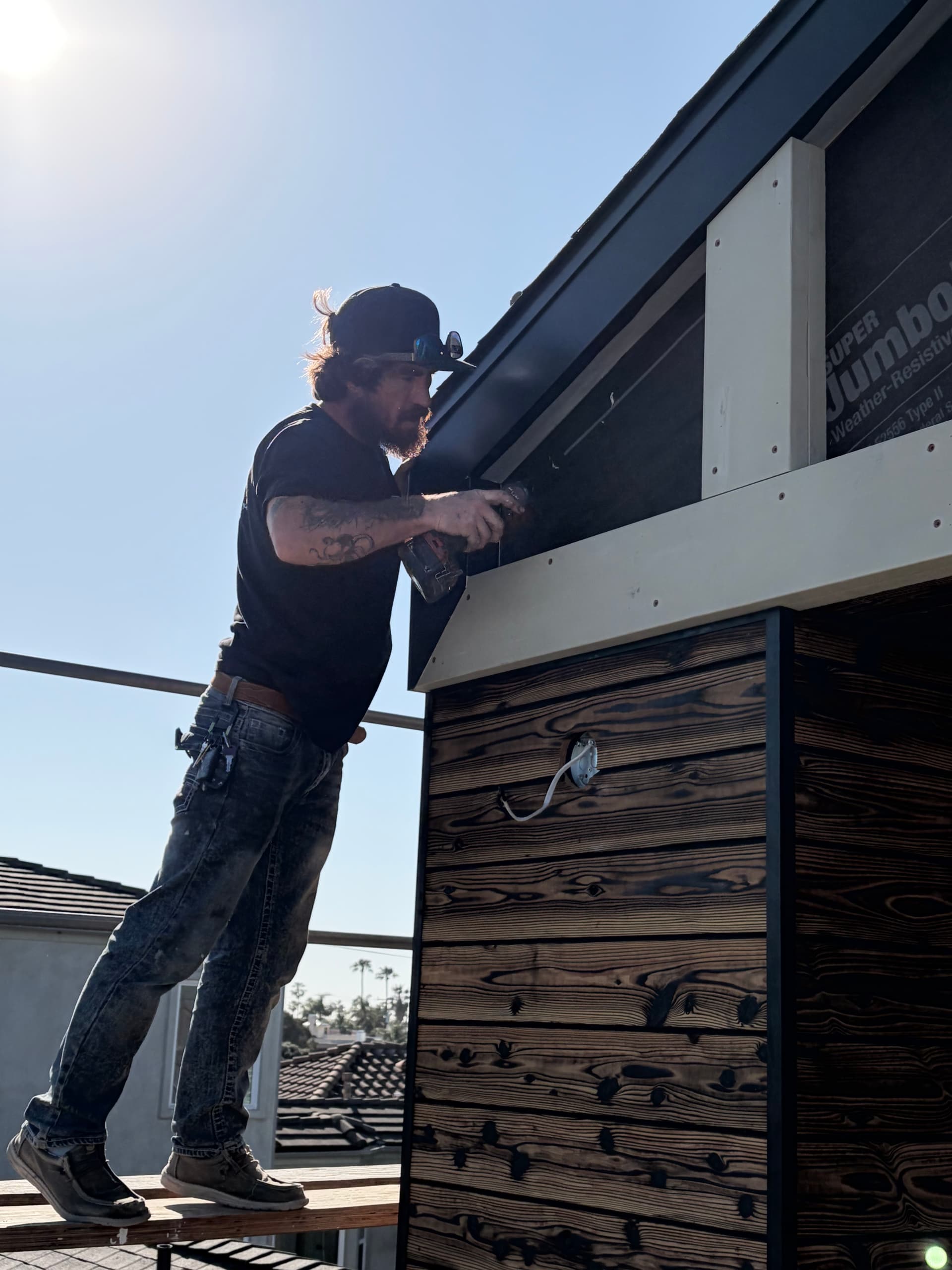 Installer fitting aluminum clad fascia wrap under wood soffit eave