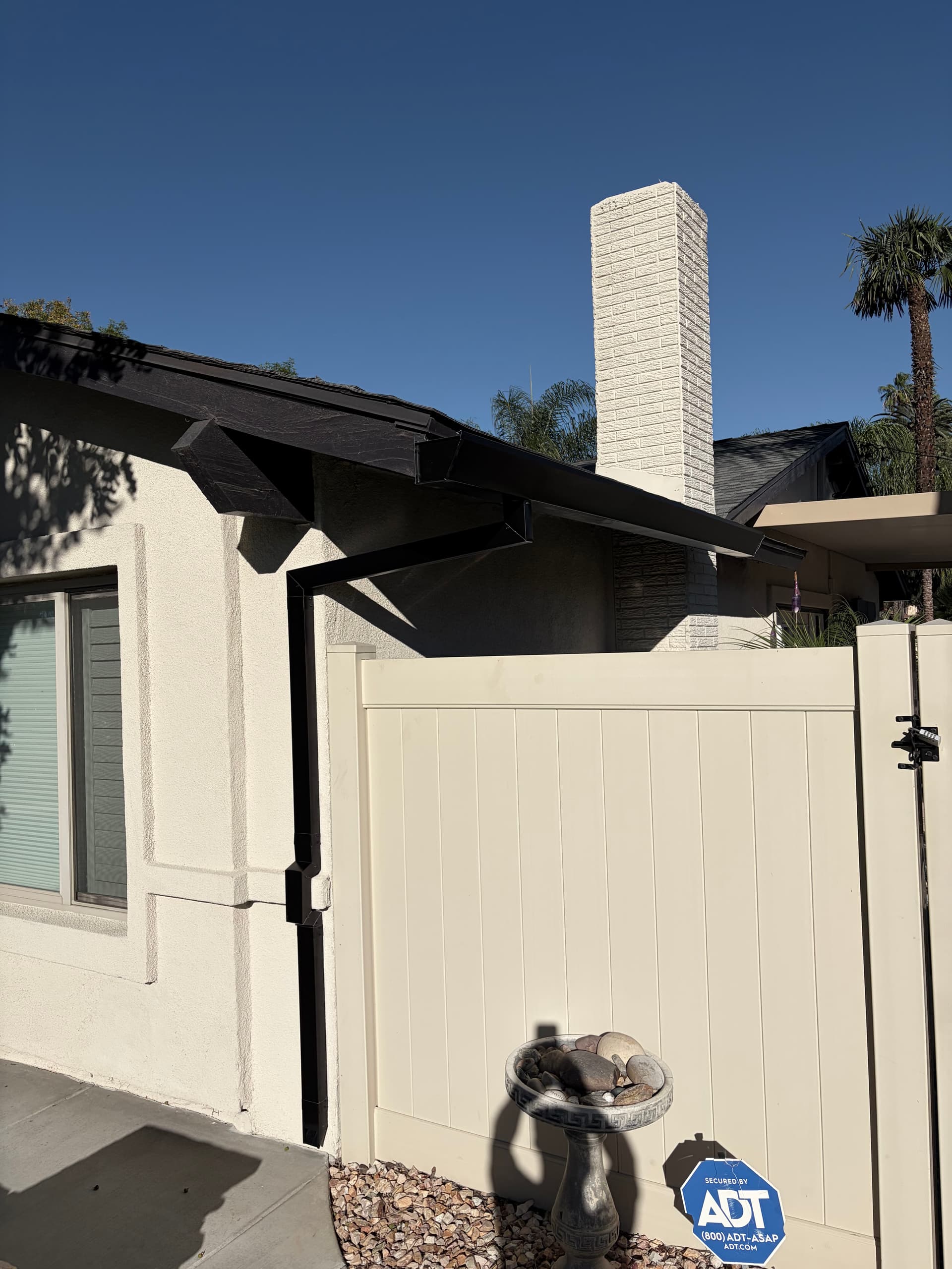 Dark seamless gutter with square downspout on a craftsman-style home