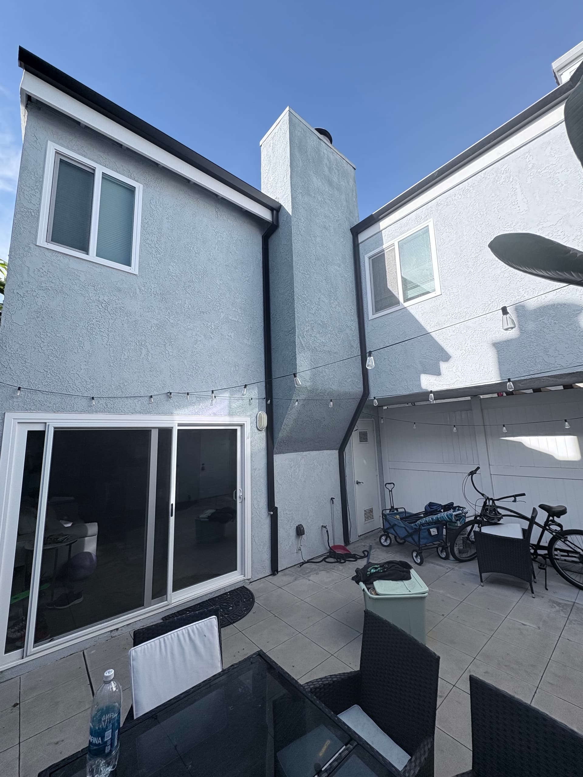 Dark seamless gutter wrapping a corner eave on a gray stucco home